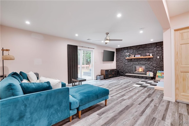 living room featuring a fireplace, light wood-type flooring, and ceiling fan