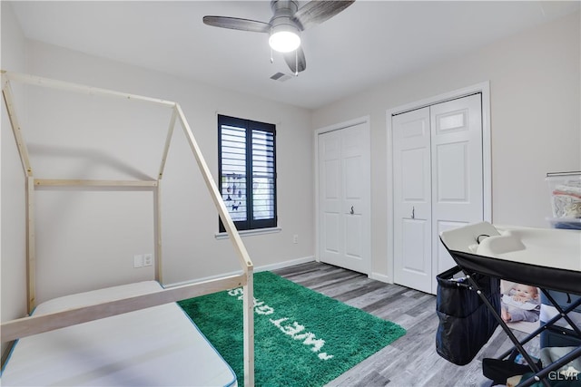 interior space with hardwood / wood-style floors, multiple closets, and ceiling fan