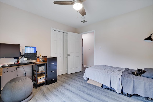 bedroom with a closet, light hardwood / wood-style floors, and ceiling fan