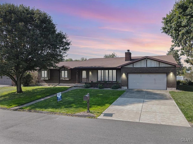 ranch-style house featuring a garage and a lawn