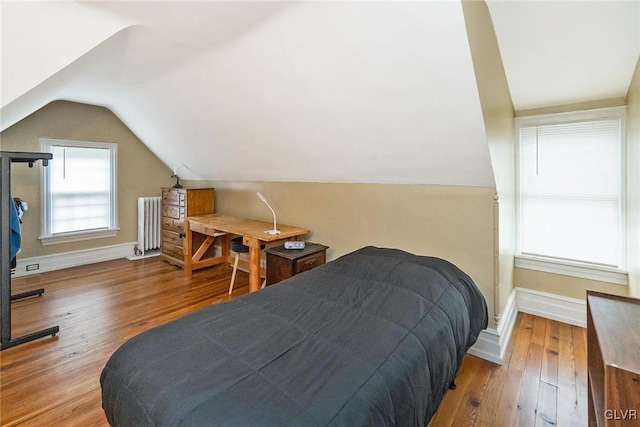 bedroom with radiator, lofted ceiling, and hardwood / wood-style flooring