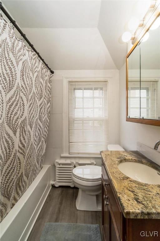 full bathroom with vanity, toilet, hardwood / wood-style flooring, vaulted ceiling, and shower / tub combo with curtain