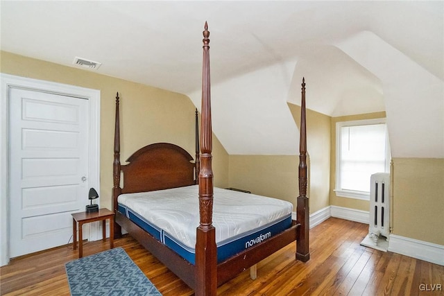 bedroom with radiator, vaulted ceiling, and hardwood / wood-style floors