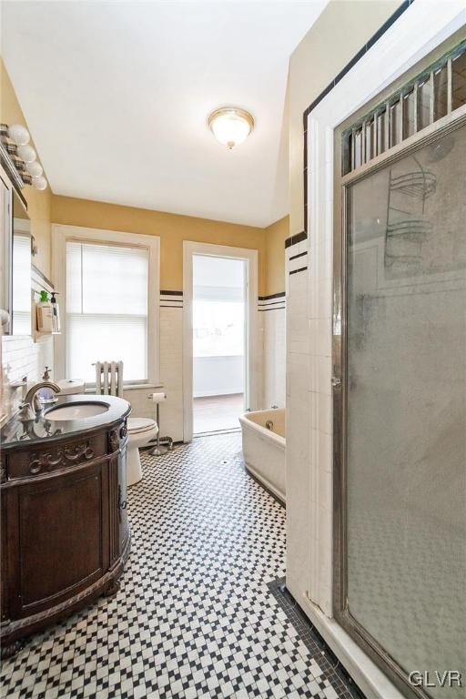 full bathroom featuring independent shower and bath, vanity, and toilet