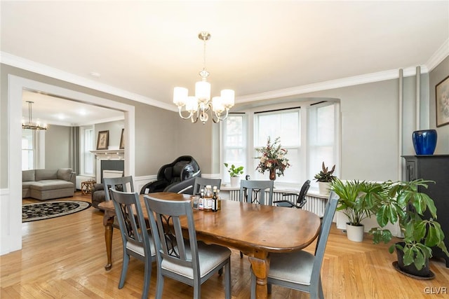 dining area featuring ornamental molding, light wood-type flooring, and a chandelier