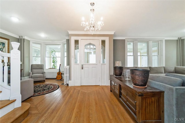 entryway with crown molding, radiator, an inviting chandelier, and light hardwood / wood-style flooring