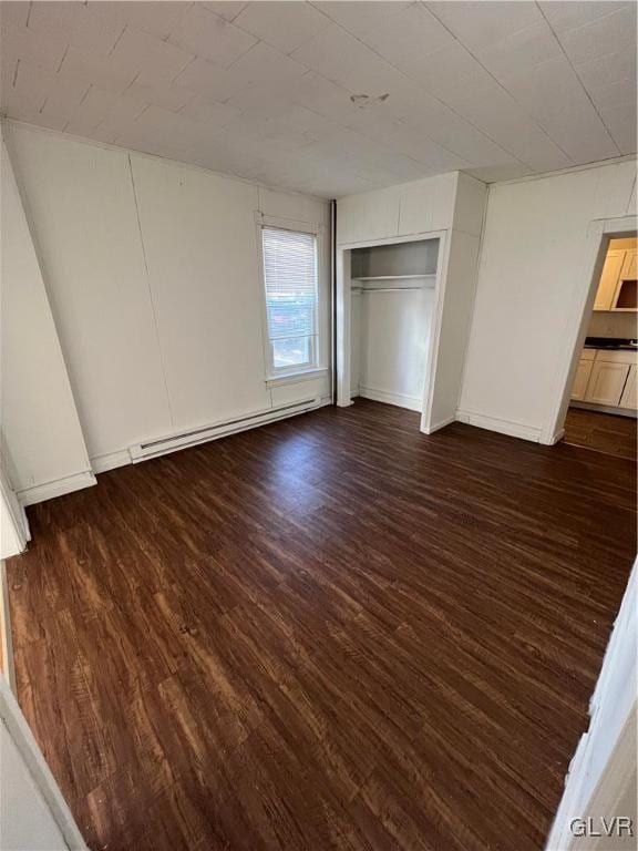 unfurnished bedroom with dark hardwood / wood-style floors, a closet, and a baseboard radiator