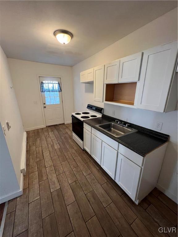 kitchen featuring white electric range oven, dark wood-type flooring, sink, and white cabinets