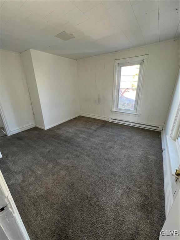 carpeted empty room featuring a baseboard radiator