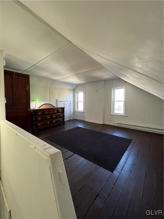 bonus room featuring a baseboard heating unit, lofted ceiling, plenty of natural light, and dark wood-type flooring