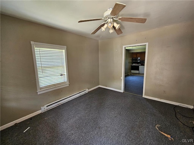 spare room featuring dark carpet, ceiling fan, and a baseboard heating unit