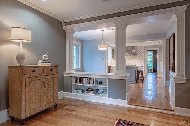 kitchen with backsplash, light hardwood / wood-style floors, wall chimney exhaust hood, pendant lighting, and ornamental molding