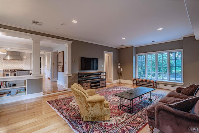 living room with crown molding, decorative columns, and light wood-type flooring