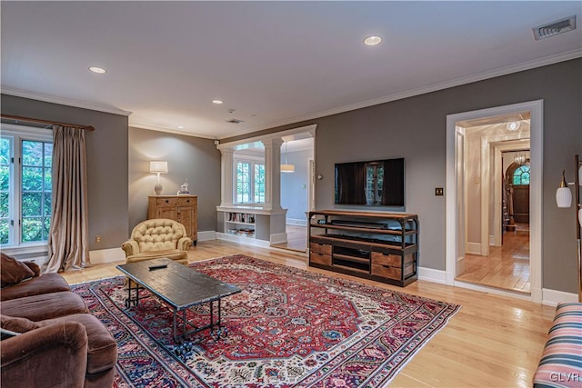 living room featuring crown molding, ornate columns, and light wood-type flooring