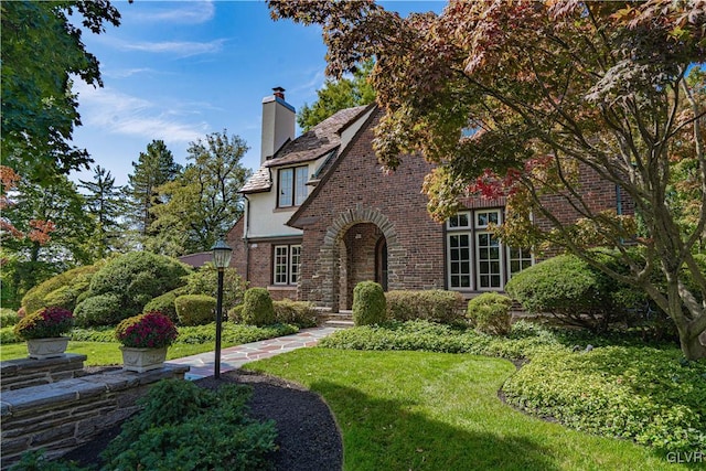 tudor-style house featuring a front yard