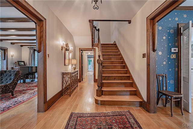 stairway with hardwood / wood-style flooring and beamed ceiling