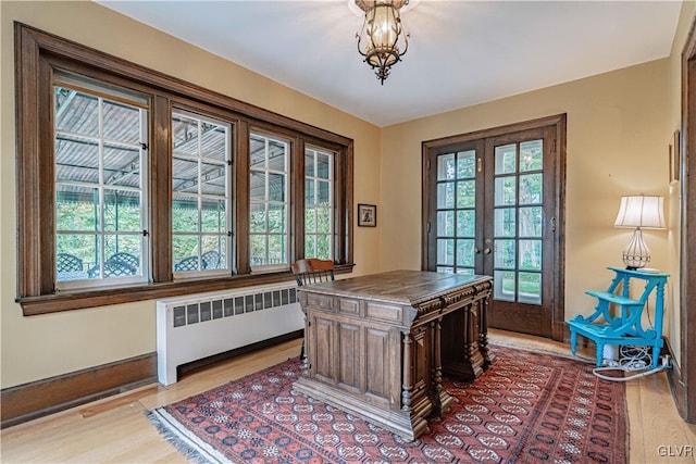 office area with light hardwood / wood-style flooring, radiator heating unit, french doors, and a wealth of natural light