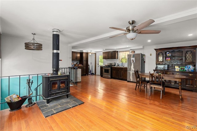 living room with light hardwood / wood-style flooring, a wood stove, and ceiling fan