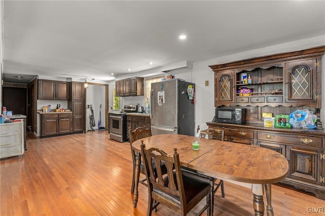 dining room featuring light wood-type flooring and crown molding