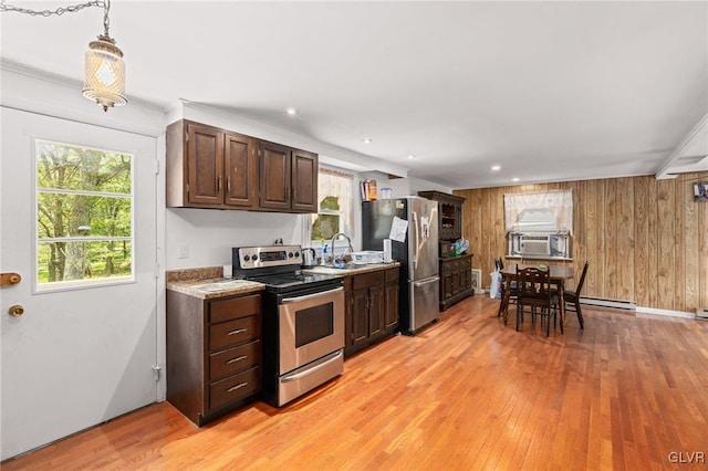 kitchen featuring appliances with stainless steel finishes, light hardwood / wood-style floors, pendant lighting, dark brown cabinetry, and wooden walls