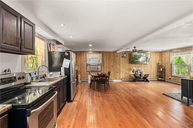 kitchen with ceiling fan, dark brown cabinetry, wood walls, light hardwood / wood-style flooring, and stainless steel appliances