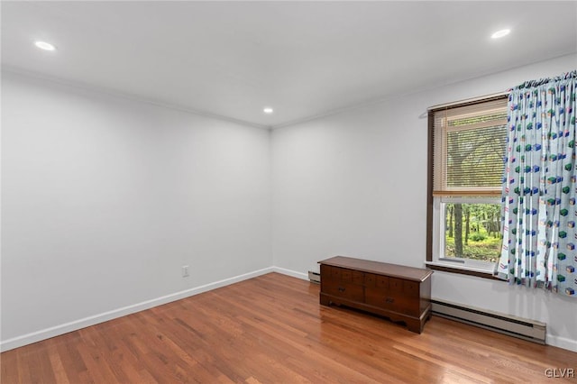 unfurnished room featuring light hardwood / wood-style flooring and a baseboard heating unit