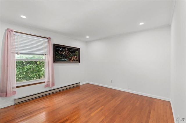 unfurnished room with ornamental molding, hardwood / wood-style floors, and a baseboard heating unit