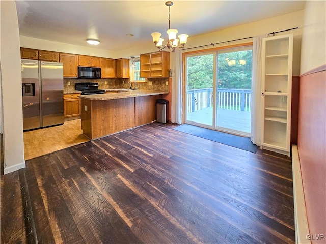 kitchen featuring pendant lighting, kitchen peninsula, tasteful backsplash, black appliances, and an inviting chandelier