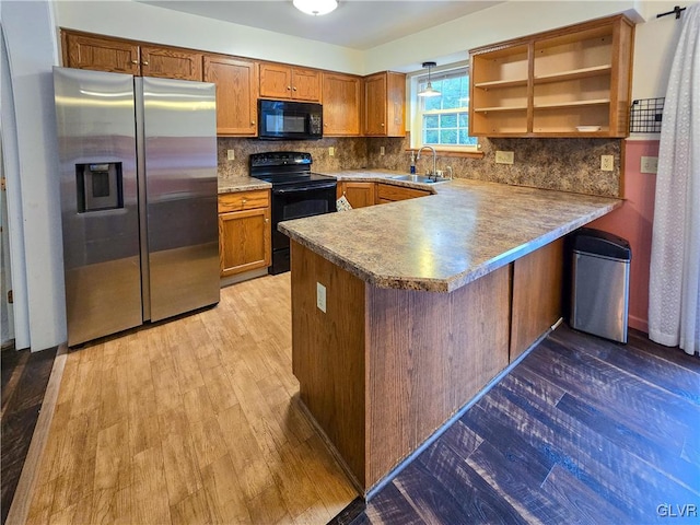 kitchen with light hardwood / wood-style floors, tasteful backsplash, sink, kitchen peninsula, and black appliances