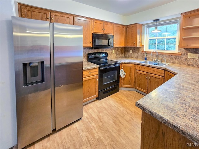 kitchen with decorative backsplash, light hardwood / wood-style floors, pendant lighting, black appliances, and sink