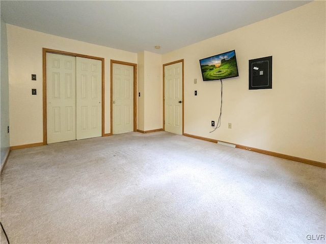 unfurnished bedroom with electric panel, two closets, and carpet flooring