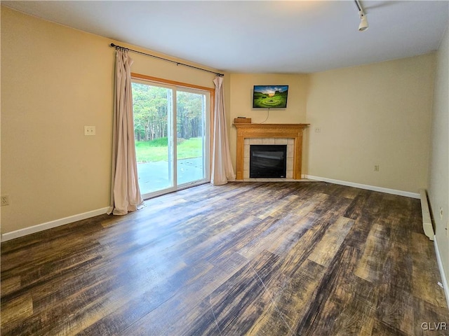 unfurnished living room with track lighting, a fireplace, baseboard heating, and dark hardwood / wood-style flooring