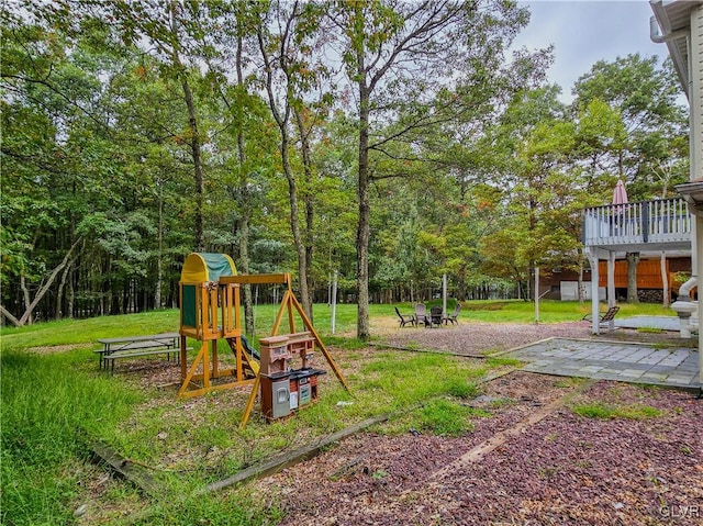 view of play area featuring a wooden deck, a lawn, and a patio