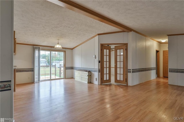 interior space with light wood-type flooring, a textured ceiling, and ornamental molding