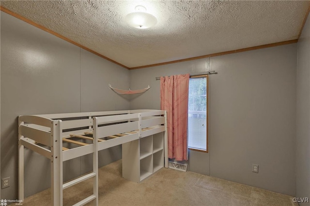 unfurnished bedroom featuring ornamental molding, a textured ceiling, and light colored carpet