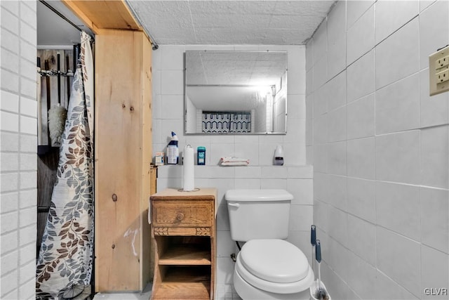 bathroom featuring tile walls and toilet