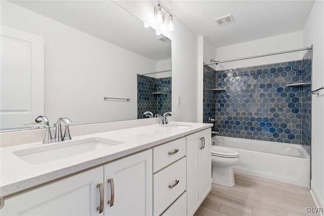 full bathroom featuring tiled shower / bath, vanity, toilet, and hardwood / wood-style flooring