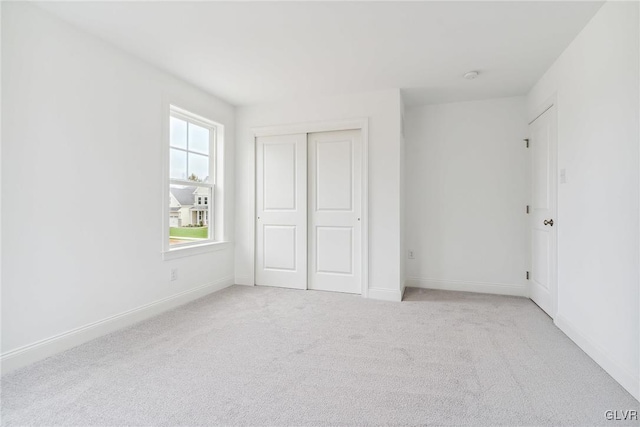 unfurnished bedroom featuring light carpet and a closet