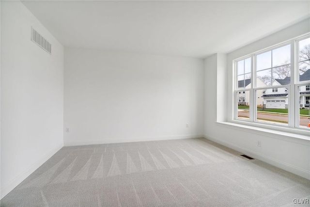 unfurnished room with light colored carpet and a healthy amount of sunlight