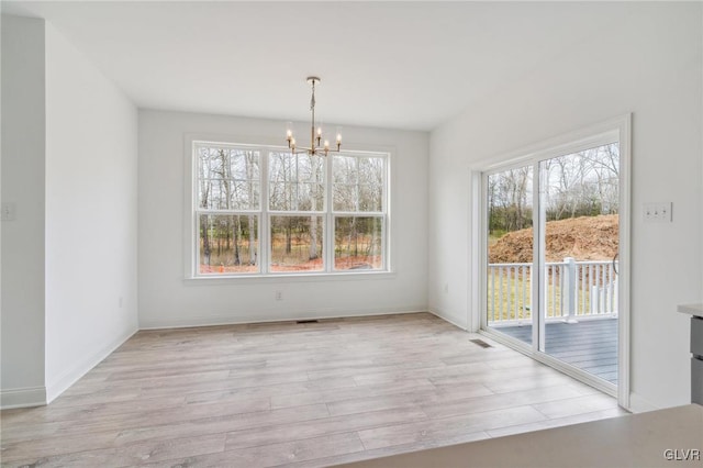 unfurnished dining area with light wood-type flooring and an inviting chandelier