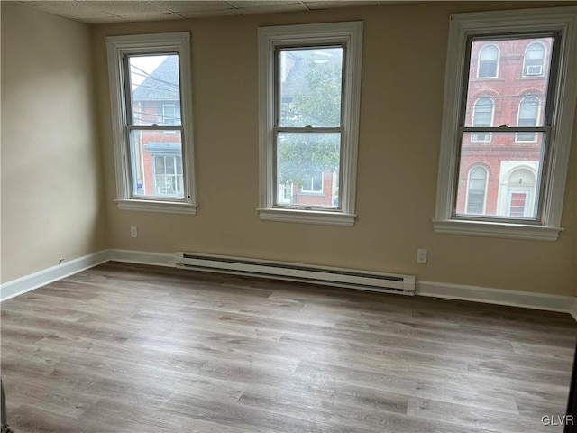 spare room with light hardwood / wood-style floors, baseboard heating, and plenty of natural light