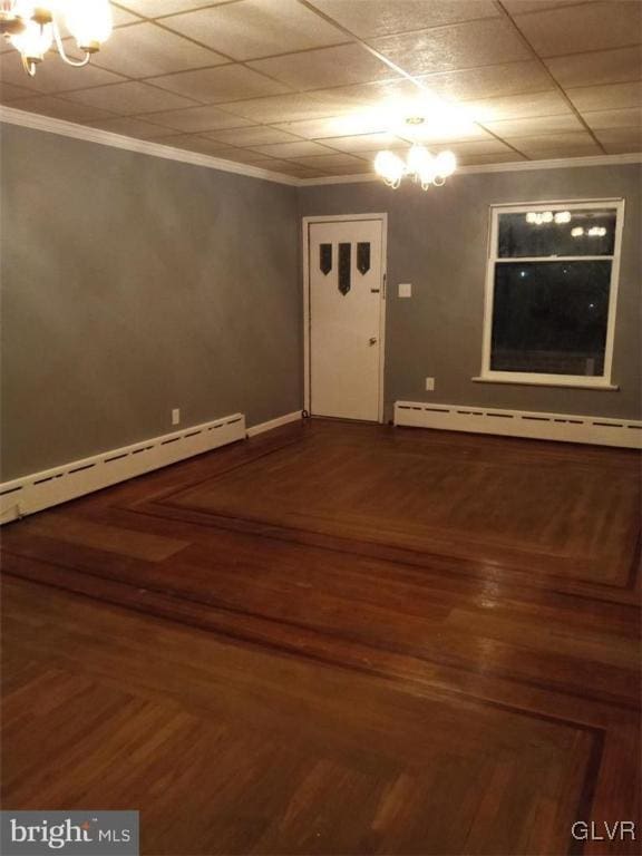 empty room with hardwood / wood-style flooring, ornamental molding, and a baseboard heating unit