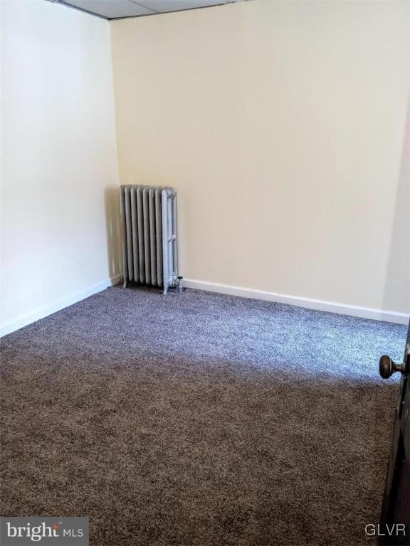 carpeted spare room with radiator heating unit