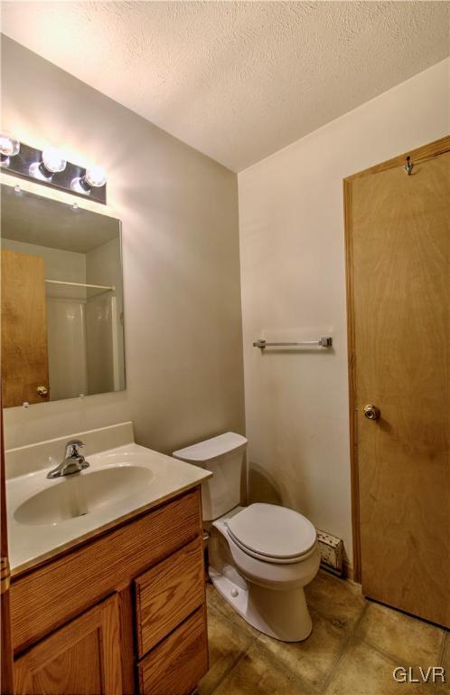 bathroom with vanity, a shower, a textured ceiling, and toilet