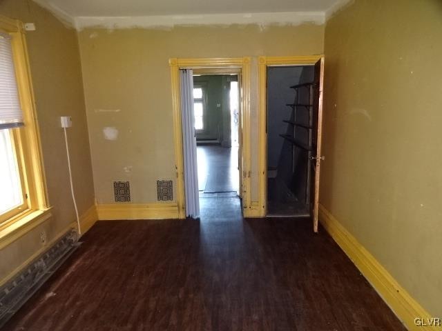 spare room featuring crown molding, dark hardwood / wood-style flooring, and a wealth of natural light