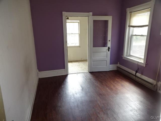 spare room with a baseboard radiator and dark hardwood / wood-style flooring