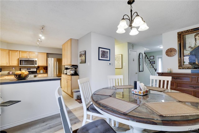 dining room featuring a notable chandelier, light wood-type flooring, and a textured ceiling