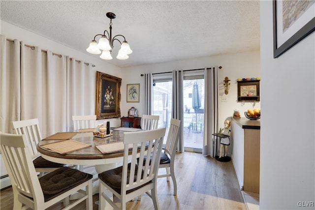 dining space featuring an inviting chandelier, light wood-type flooring, and a textured ceiling