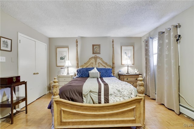 bedroom with light parquet floors, a textured ceiling, a baseboard heating unit, and a closet