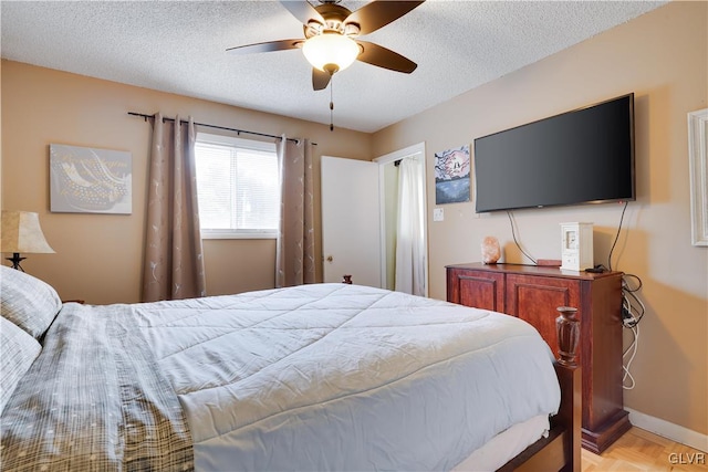 bedroom featuring ceiling fan, light parquet flooring, and a textured ceiling